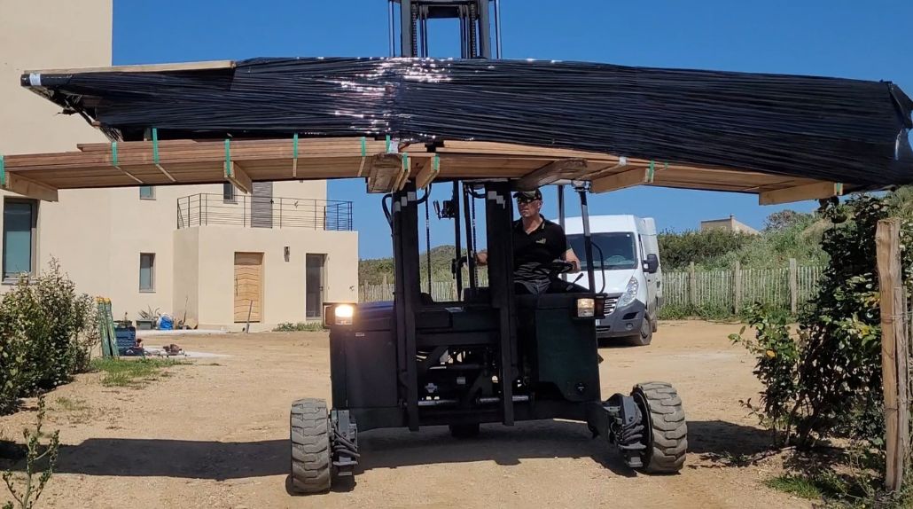 Livraison de lames de terrasse en Corse avec chariot embarqué Cargomatic sur chantier de construction