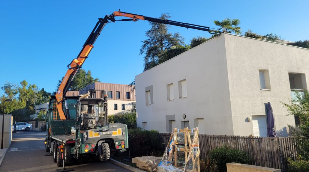 Camion Cargomatic avec grue longue portée pour livraison directe d'une véranda en étage d'un immeuble