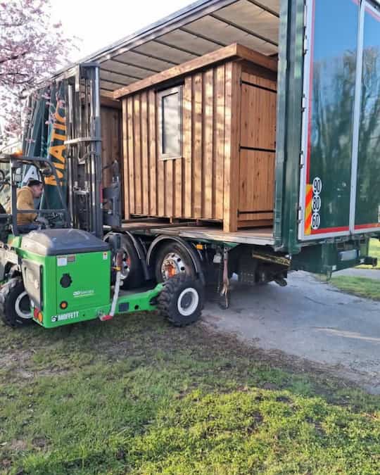 Transport Cargomatic avec chariot embarqué électrique déchargeant un abri de jardin bois directement sur site client