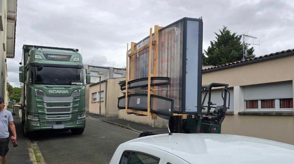 Livraison d'un abri de piscine avec chariot embarqué dans une rue étroite par un camion Cargomatic